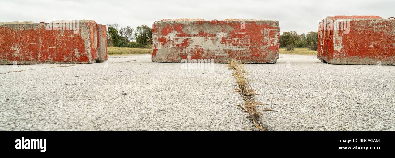 Blocchi stradali pesanti in cemento che bloccano l'autostrada o la strada. Concetto di ostacolo, vicolo cieco o ostacolo al progresso. Banner panoramico Foto Stock