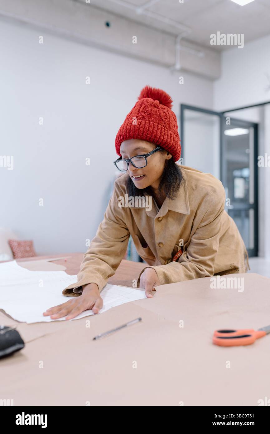 Giovane donna in abiti caldi che impara a cucire Foto Stock
