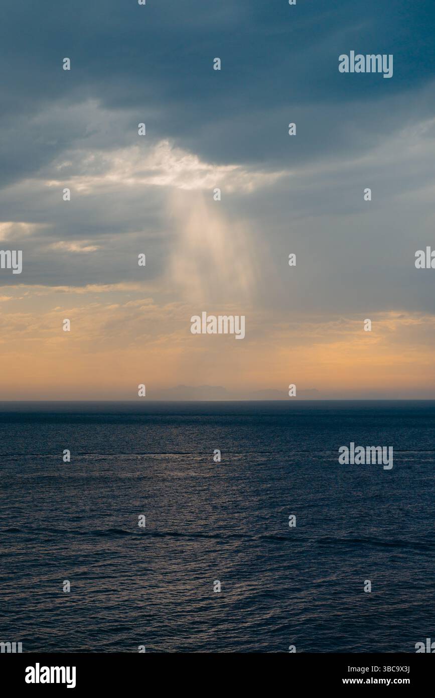 Raggi di sole che si infrangono attraverso nuvole di tempesta sul mare, Minorca Foto Stock