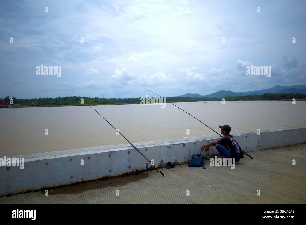 Yogyakarta - Indonesia, 20 aprile 2025: Pescatori che pescano a Congot Beach, Kulon Progo, Yogyakarta, Indonesia con struttura di demolitore a onde di cemento tetrapod Foto Stock