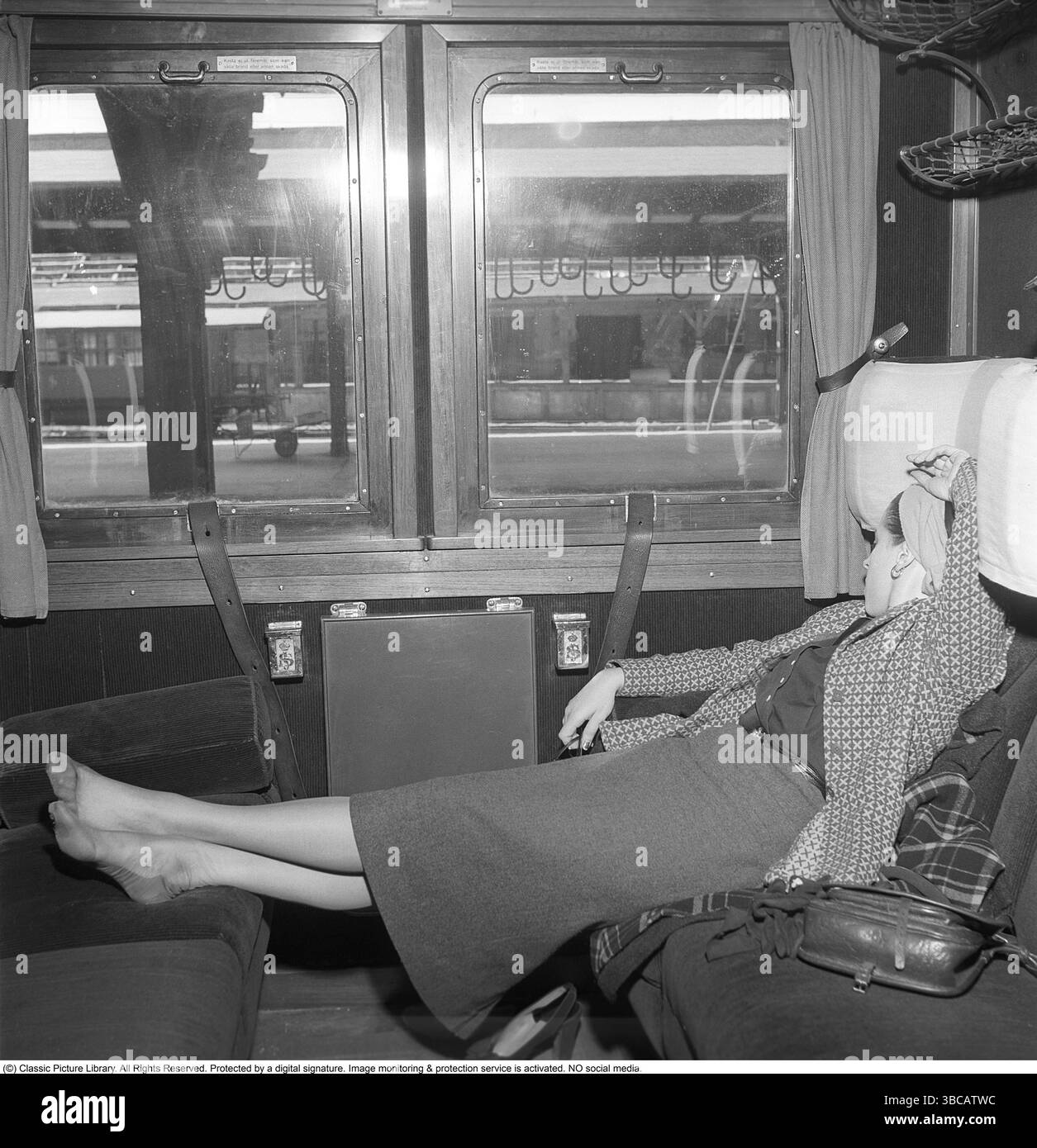 Viaggi in treno negli anni '1950 Una donna addormentata su un treno viene vista seduta con i piedi sul sedile opposto. 1955. Svahn Foto Stock