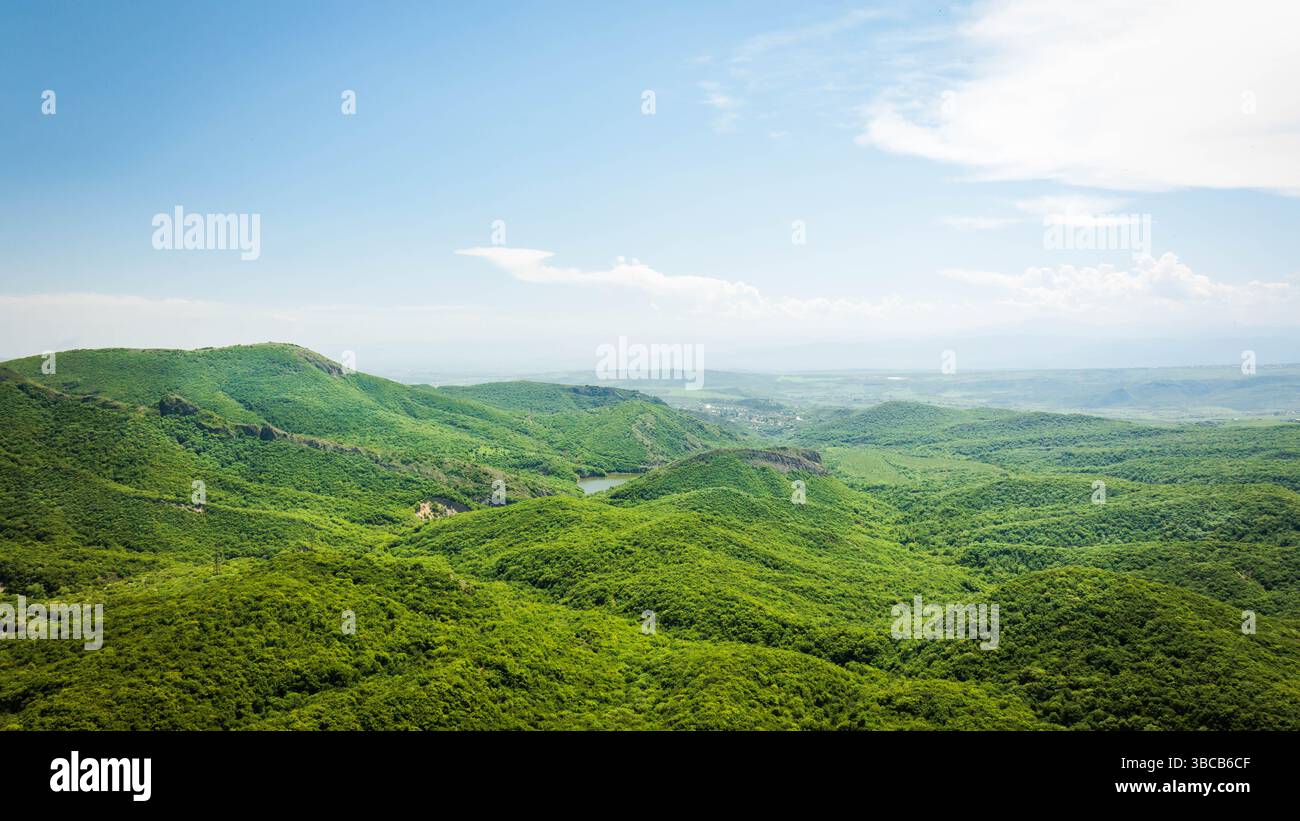 Colline verdi ondulate e un lago nascosto visto dall'alto, con nuvole che proiettano ombre morbide. Tranquillo paesaggio naturale in Georgia Foto Stock