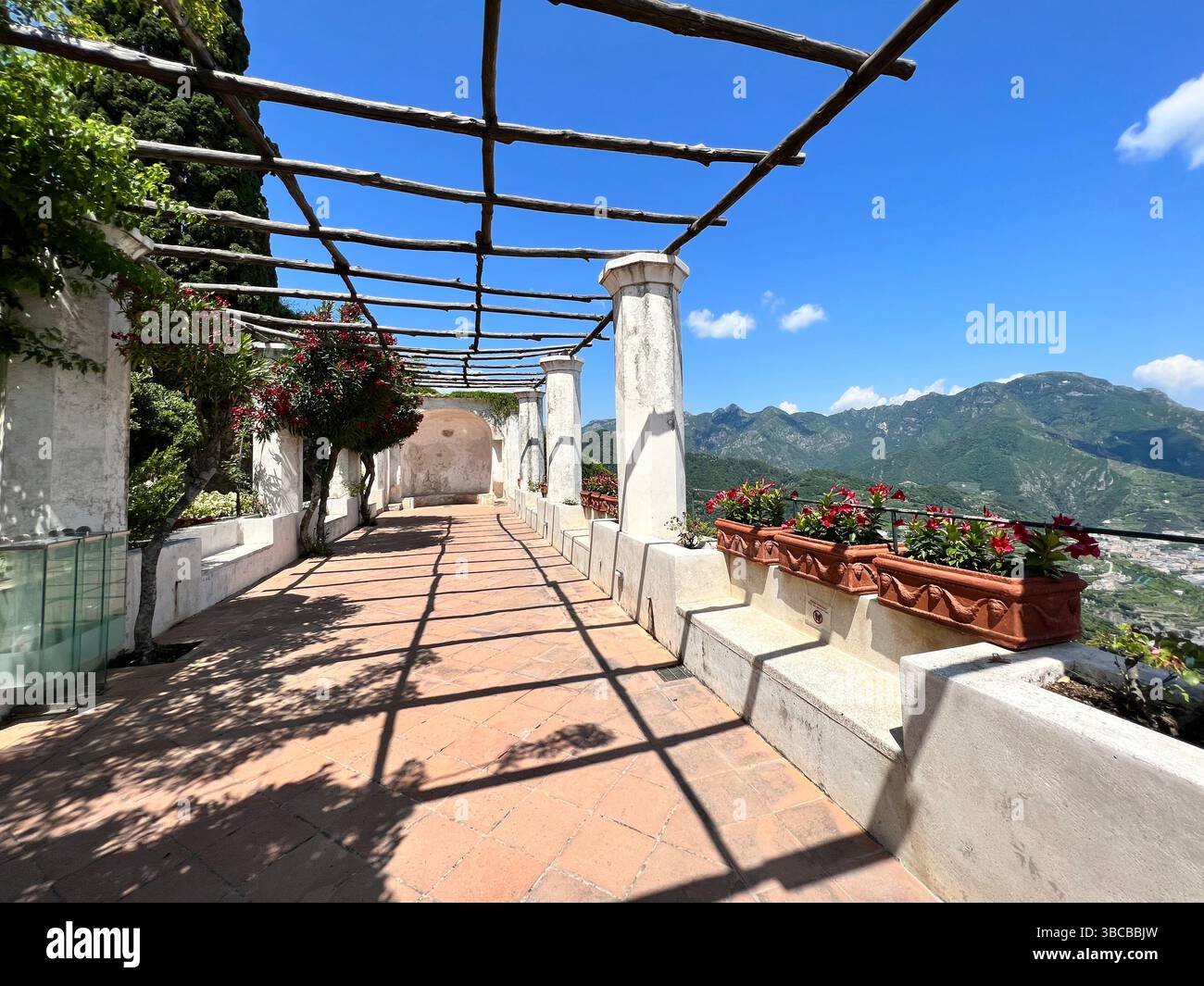 Una passeggiata a pergola soleggiata a Ravello, Italia, incornicia ampie vedute delle montagne circostanti della Costiera Amalfitana. Foto Stock