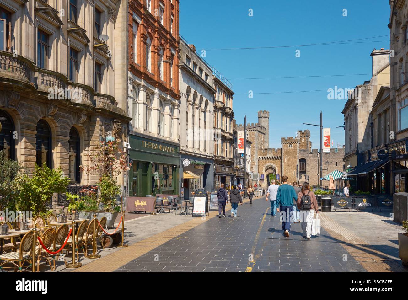 Cardiff, South Glamorgan, Galles, Europa - 9 maggio 2025: Amanti dello shopping in St Mary's Street in una giornata di sole con castello sullo sfondo. Foto Stock