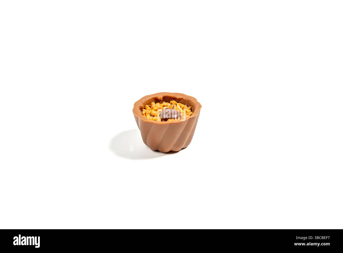 Pralina con nocciole Single Shot su sfondo bianco. Questa delicata pralina è fatta di cioccolato al latte e ripiena di pezzi di nocciole croccanti. Foto Stock