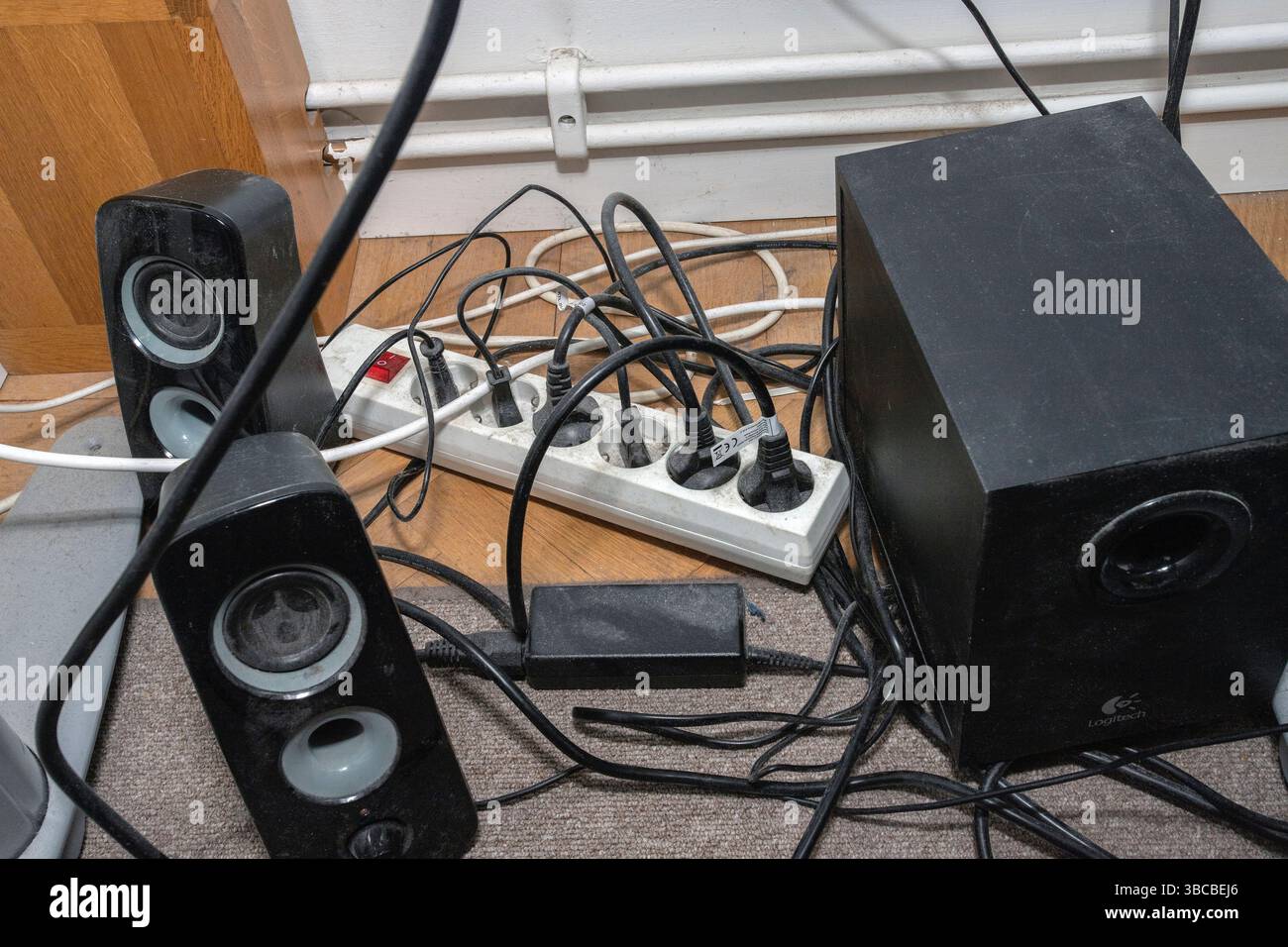 Un cavo di prolunga elettrico polveroso pieno di spine di alimentazione può rappresentare un pericolo di incendio. Foto Stock