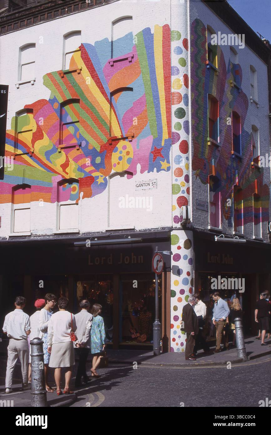 1967, esterno della boutique di moda, Lord John, angolo tra Ganton St e Carnaby St, Westminster, Londra, Inghilterra, Regno Unito. Il rivenditore era stato fondato alcuni anni prima, nel 1963, dai fratelli Warren, Harold e David Gold. All'esterno, un murale pischedelico dipinto da un collettivo BEV, creato dall'artista David Vaughan. Il rivenditore di moda Lord John era un negozio popolare per la folla di moda e le principali figure musicali dell'epoca. Foto Stock