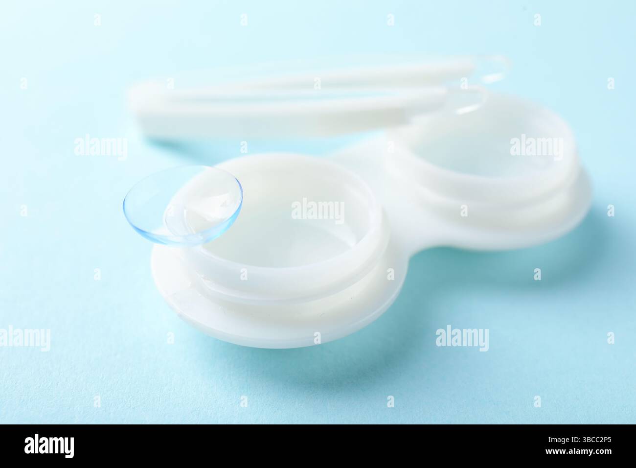 Lenti a contatto, custodia e pinzette su sfondo azzurro, primo piano Foto Stock