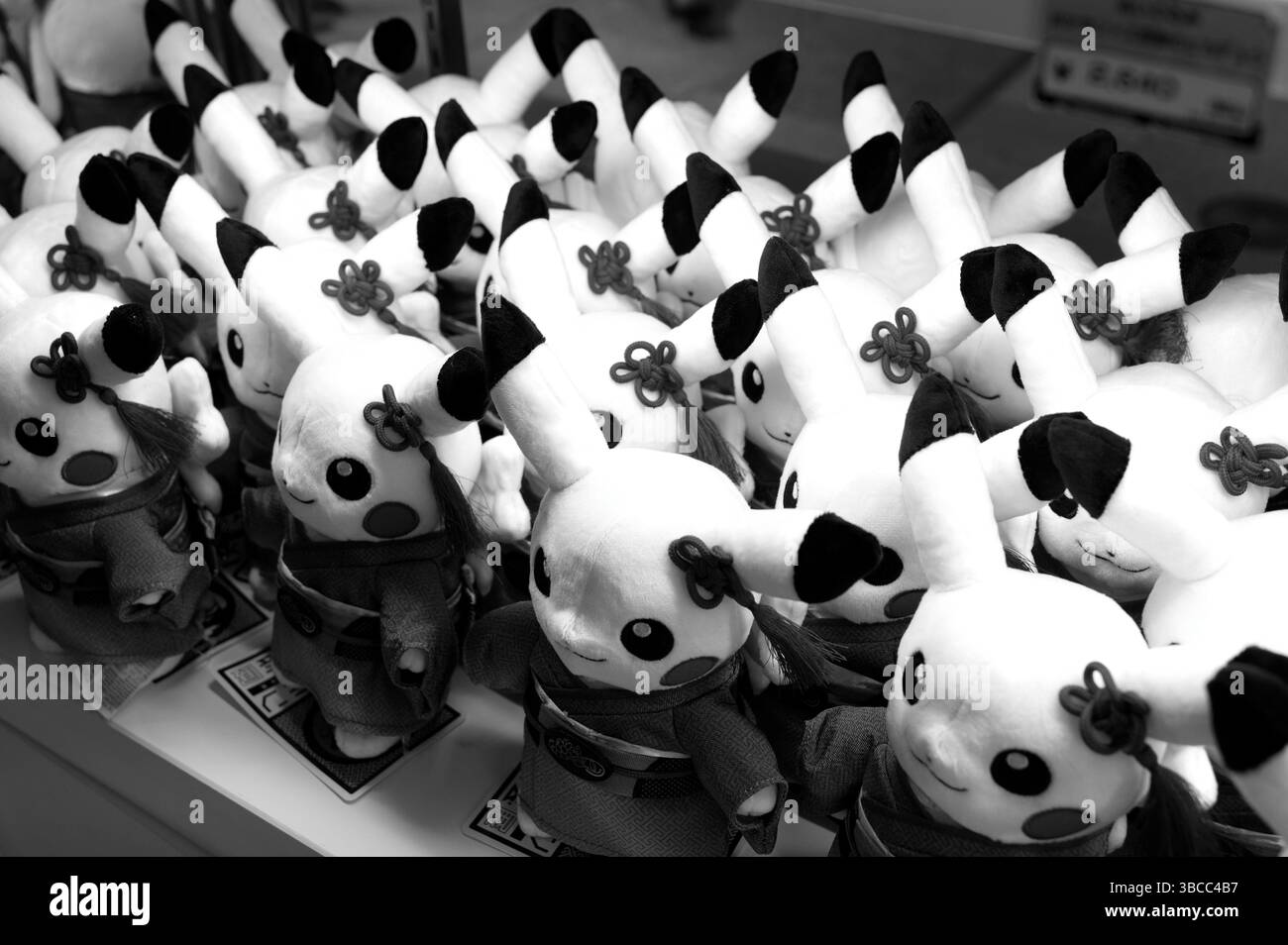File di Pikachu plushies rivestite di kimono sono orgogliosamente in formazione in bianco e nero Foto Stock