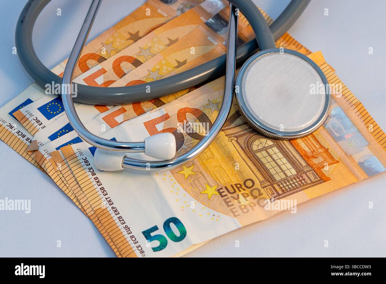 Stetoscopio su banconote da € 50 su sfondo bianco. Foto Stock