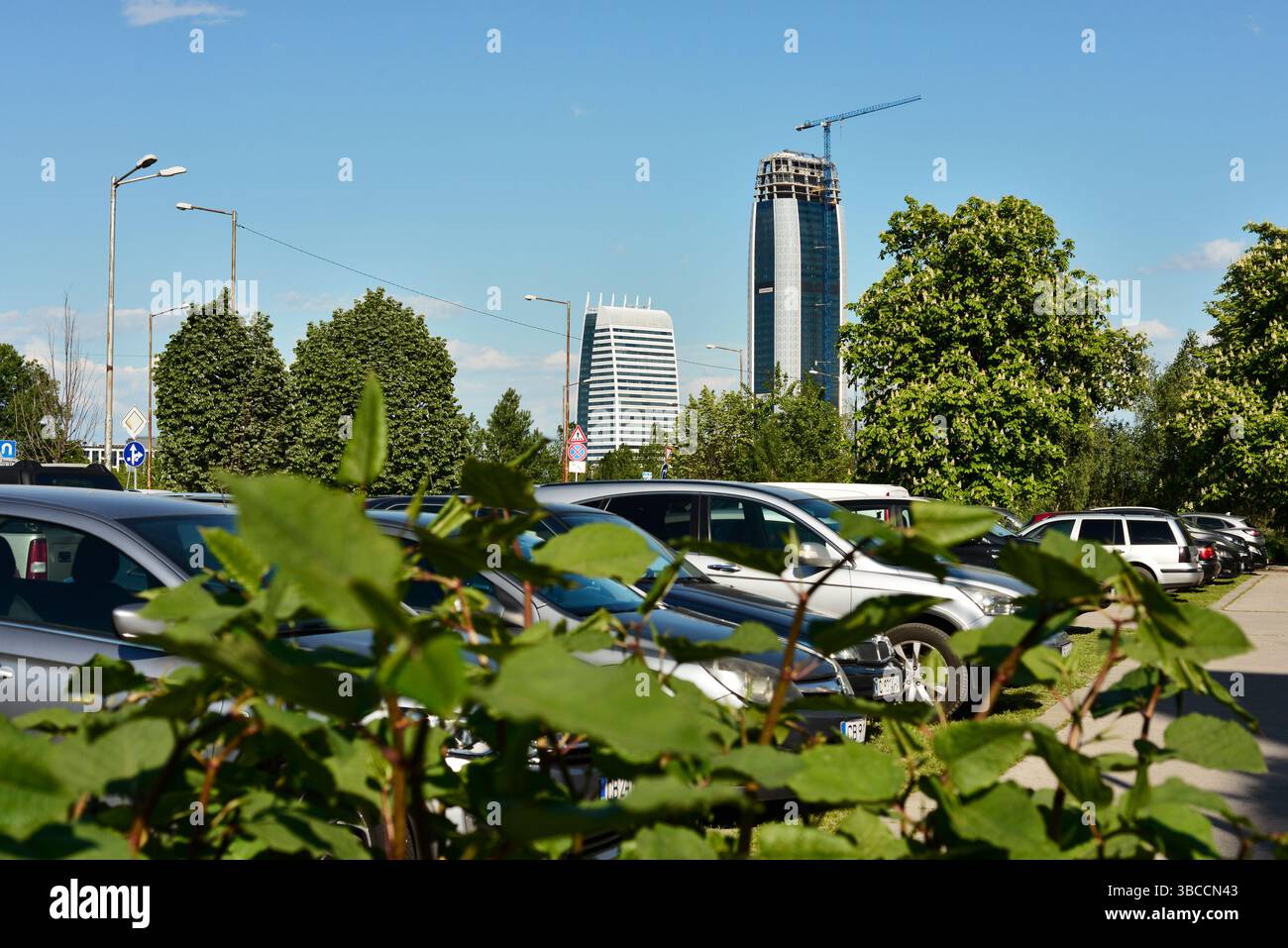 Moderni edifici per uffici a Sofia, Bulgaria, visti attraverso un parcheggio auto e il verde, riflettono lo sviluppo delle infrastrutture urbane e la crescita aziendale Foto Stock