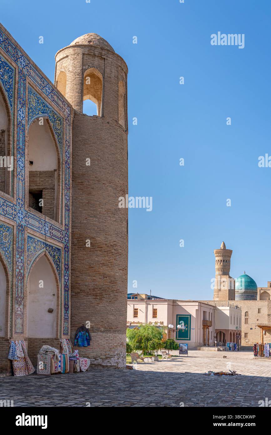 Un cortile illuminato dal sole con gallerie ad arco circonda la Madrasa Abdulazizkhan a Bukhara, Uzbekistan, che riflette secoli di studio islamico. Foto Stock