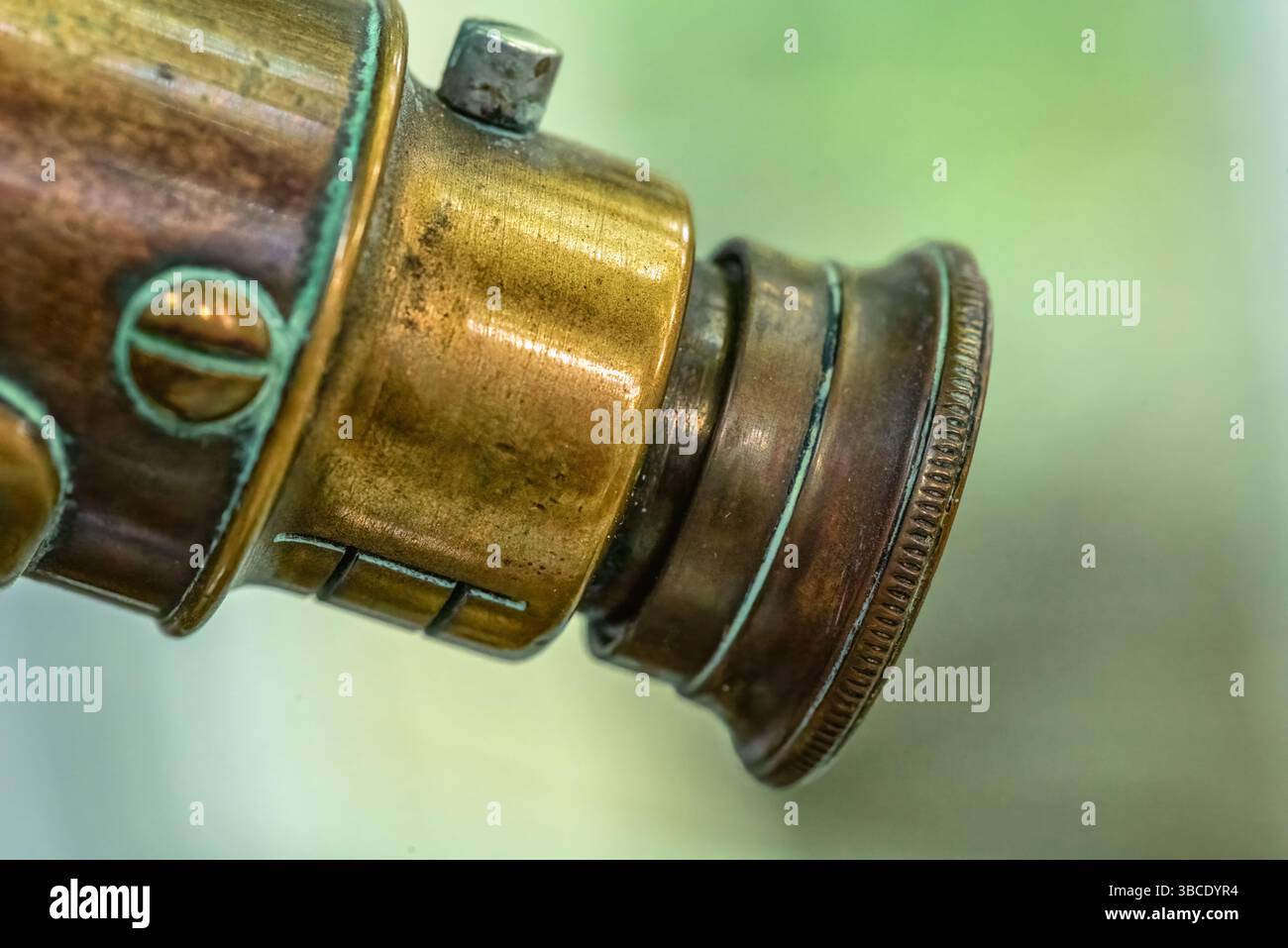 Primo piano di un oculare ottico in ottone di uno strumento scientifico vintage, che mostra metallo invecchiato, dettagli fini e patina verde. Foto Stock