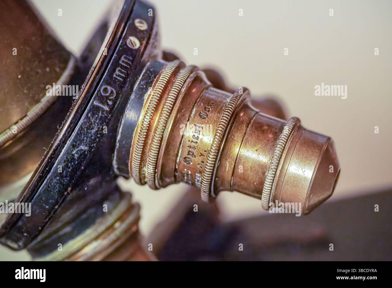 Primo piano di una lente ottica vintage contrassegnata da 19 mm con testo inciso e raccordi in ottone testurizzato, parte di uno storico strumento scientifico. Foto Stock
