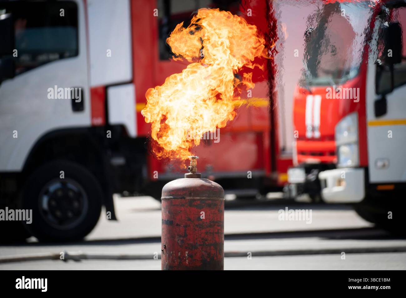 Il serbatoio GPL è in fiamme. una bombola di gas in metallo bruciato sullo sfondo di un camion antincendio. Situazione esplosiva. Foto Stock