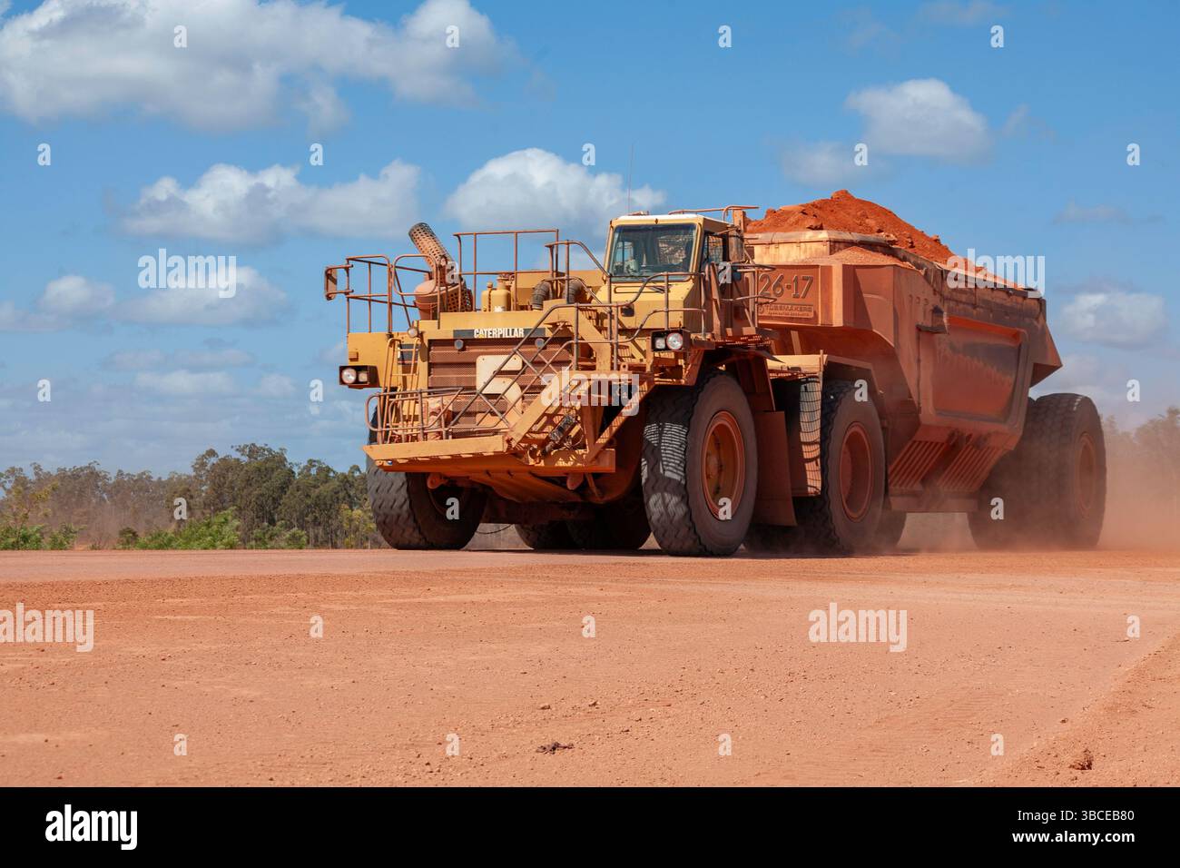 il minerale di ferro numero 5 enorme dumper da miniera pesante che passa su strada paesaggio naturale azione veicoli cielo nuvoloso weipa penisola di cape york queensland australia Foto Stock