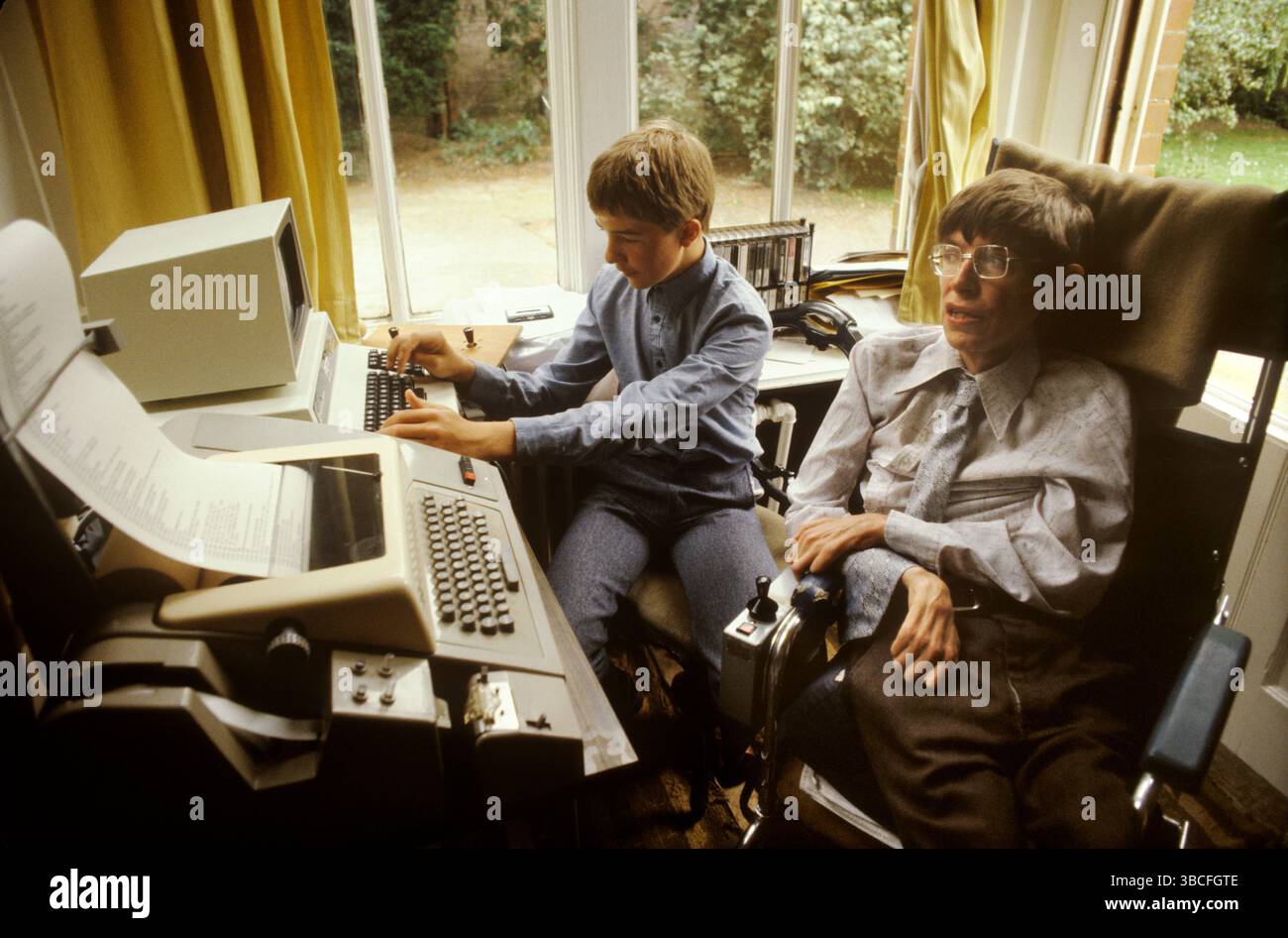 Il professor Stephen Hawking a casa con il figlio maggiore Robert. Seduto nel suo ufficio domestico con computer e una macchina per l'elaborazione di testi. Il suo ufficio faceva parte del soggiorno. Cambridge, Cambridgeshire, Inghilterra 1981,1980s UK HOMER SYKES Foto Stock