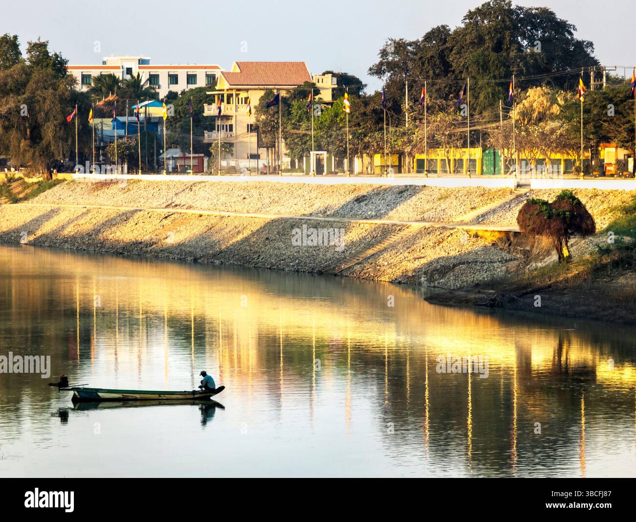 Provincia di Battambang, Cambogia - febbraio 26 2024: Nel centro della città lungo il fiume principale, un pescatore tenta la fortuna, mettendo una rete per catturare il pesce al tramonto Foto Stock