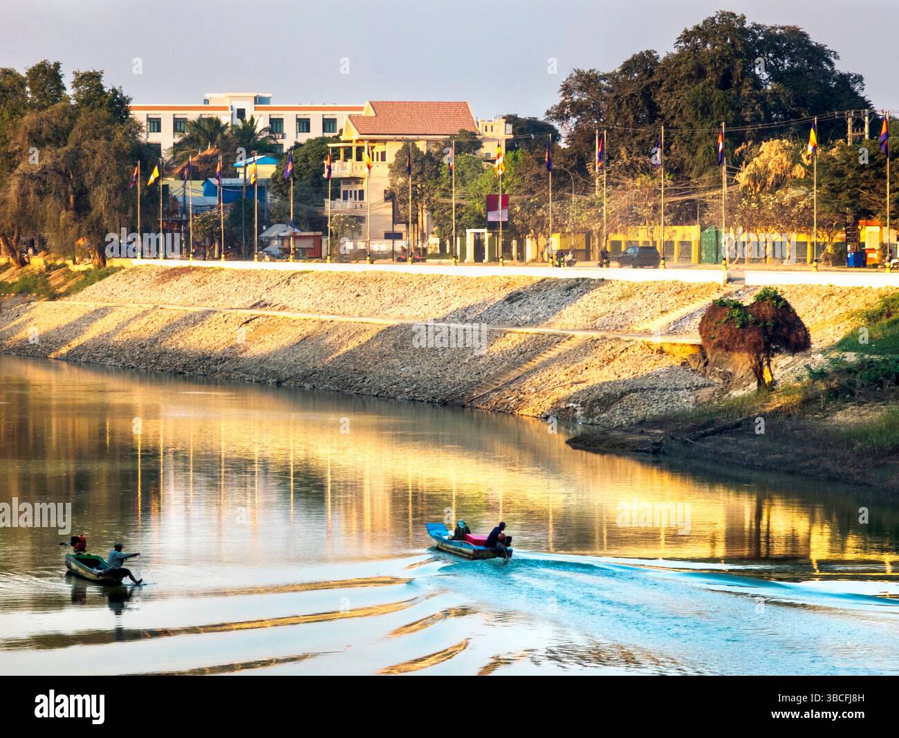 Provincia di Battambang, Cambogia - febbraio 26 2024: Nel centro della città lungo il fiume principale, un altro minuscolo motoscafo passa davanti a un pescatore che cerca la sua fortuna, mettendo fuori gioco Foto Stock