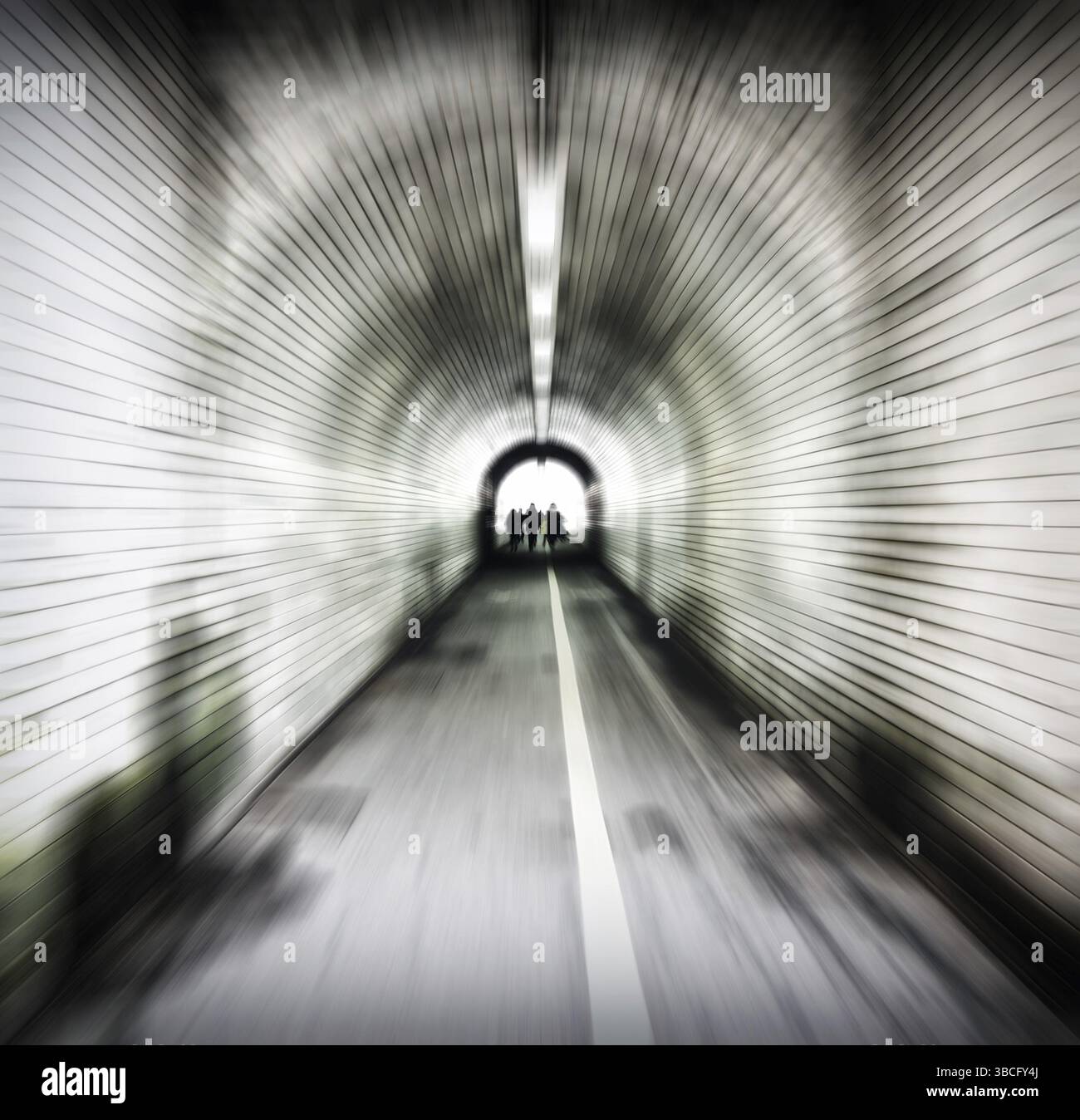 Zoom immagine sfocata di un vecchio tunnel pedonale buio con persone non identificabili che emergono nella luce Foto Stock