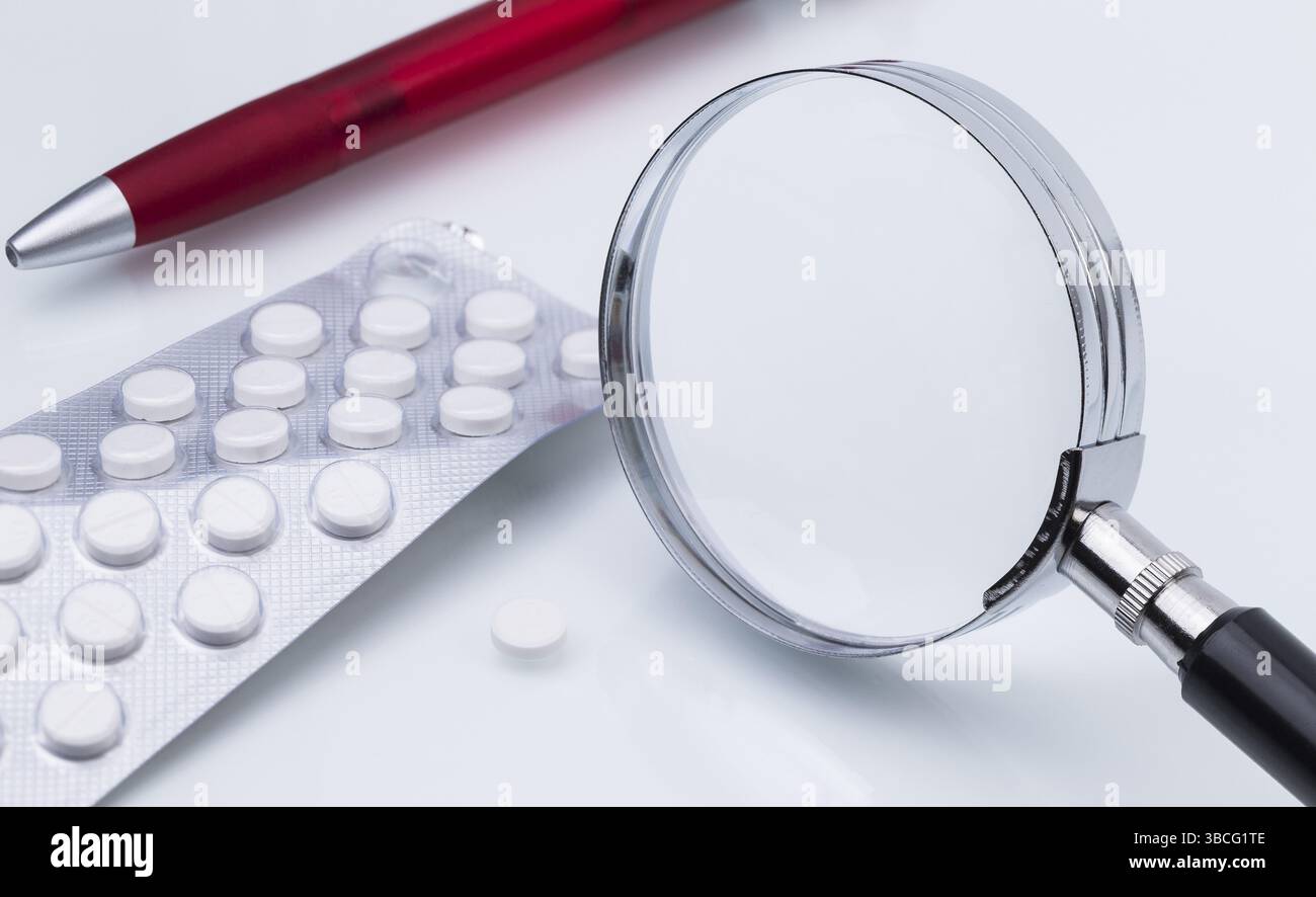 La foto mostra una confezione di tablet con una lente di ingrandimento Foto Stock