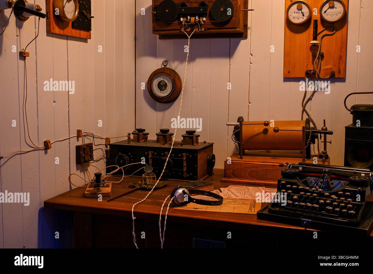 Vecchia sala radio con varie attrezzature antiche, tra cui una macchina da scrivere, cuffie e componenti elettrici, che mostrano la tecnologia di comunicazione di t Foto Stock