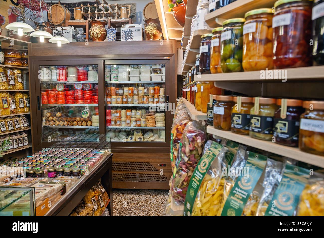 L'interno di una tradizionale gastronomia greca presenta formaggi locali, pasta fatta a mano, conserve, erbe aromatiche e prodotti gourmet ordinatamente disposti su scaffali in legno Foto Stock