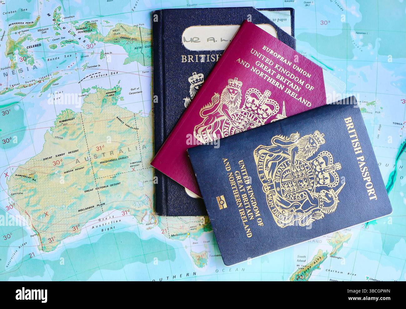 Tre passaporti del Regno Unito con due passaporti UE pre-Europen scaduti e un passaporto biometrico del Regno Unito in corso su una pagina dell'atlante dell'Australasia Foto Stock