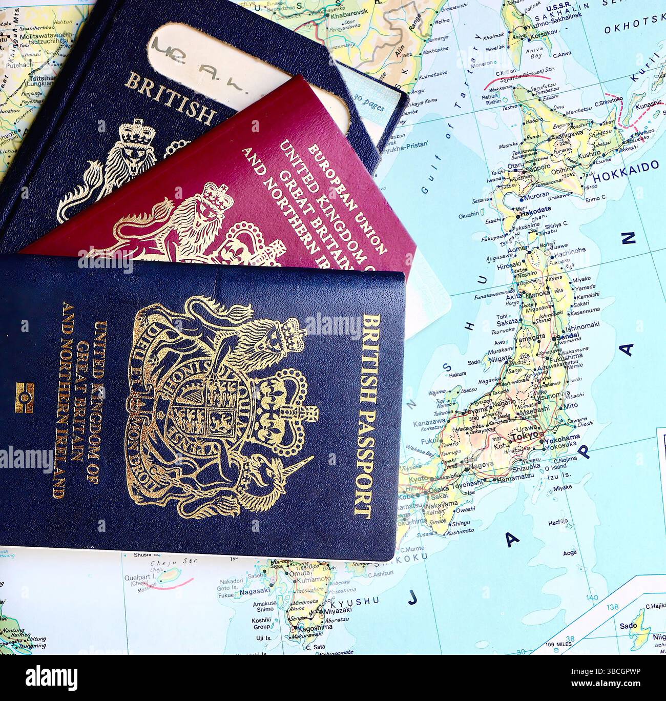 Tre passaporti del Regno Unito con due passaporti UE pre-Europen scaduti e un passaporto biometrico del Regno Unito in corso su una mappa del Giappone della pagina atlas Foto Stock