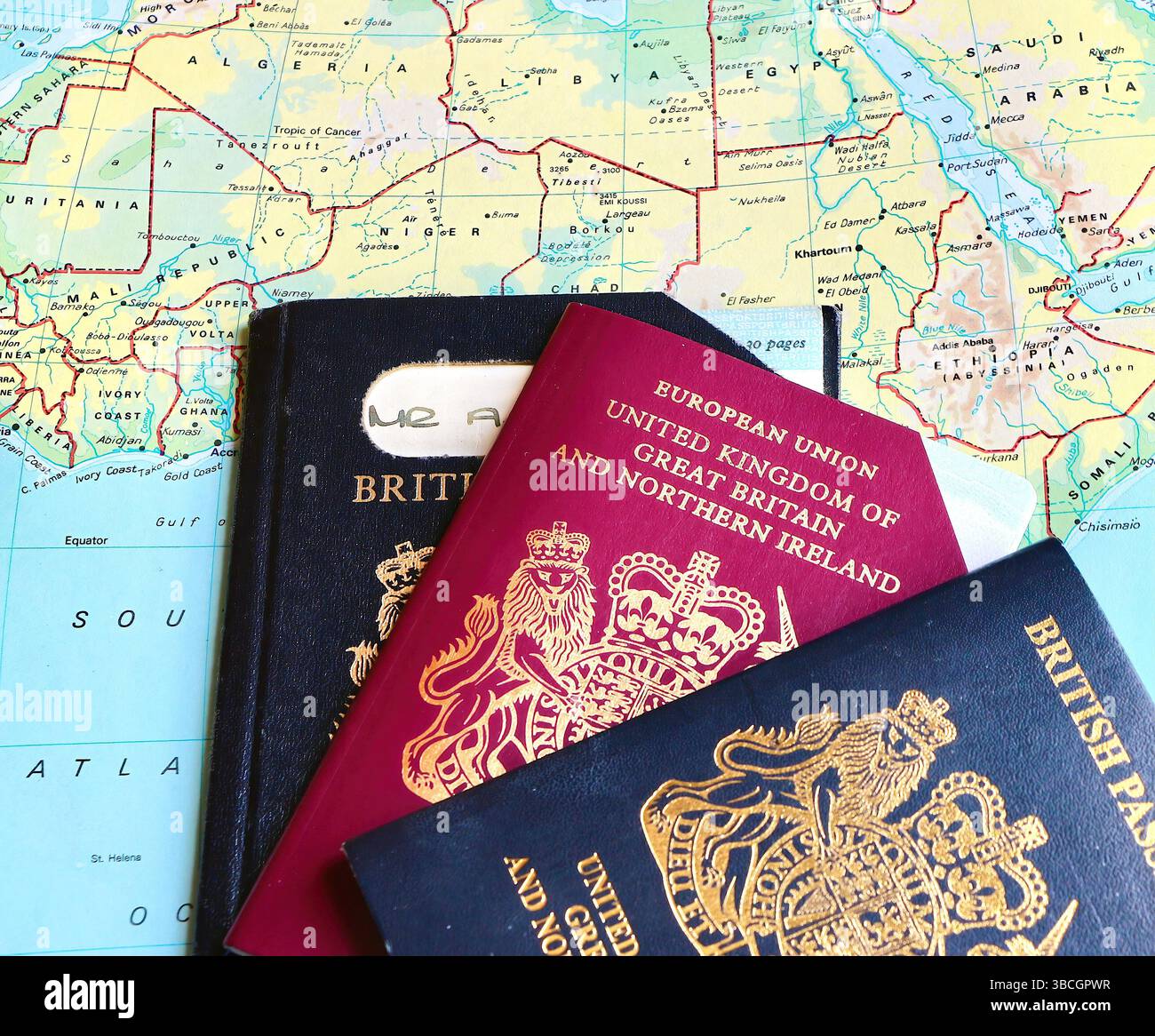 Tre passaporti del Regno Unito con due passaporti UE pre-Europen scaduti e un passaporto biometrico del Regno Unito in corso su una pagina atlas aperta in Africa Foto Stock