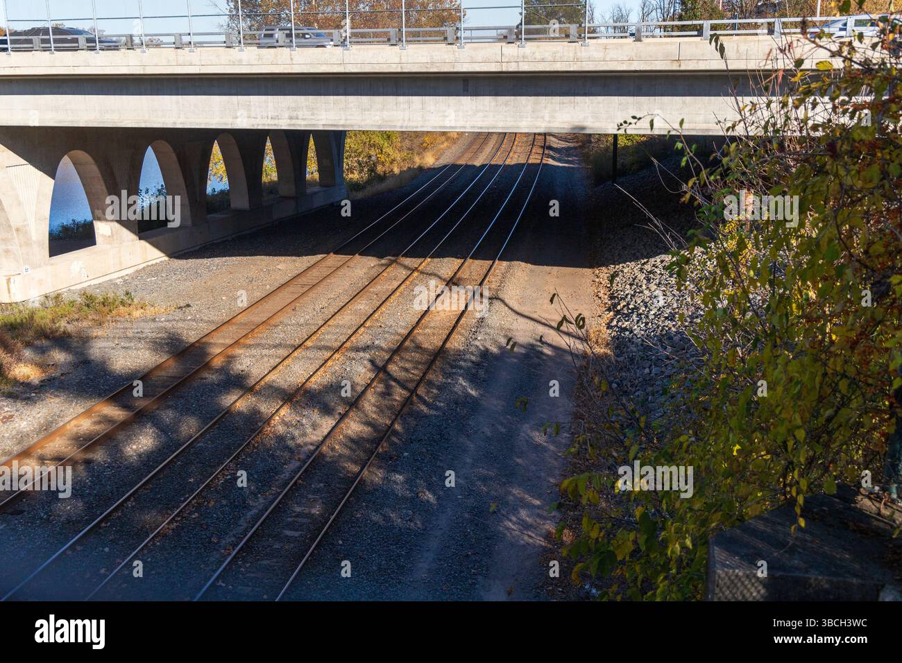 Un binario ferroviario con un ponte su un fiume. Il ponte è realizzato in cemento e ha una ringhiera metallica. I binari del treno sono in metallo e si trovano in Foto Stock Un binario ferroviario con un ponte su un fiume. Il ponte è realizzato in cemento e ha una ringhiera metallica. I binari del treno sono in metallo e si trovano in Foto Stock