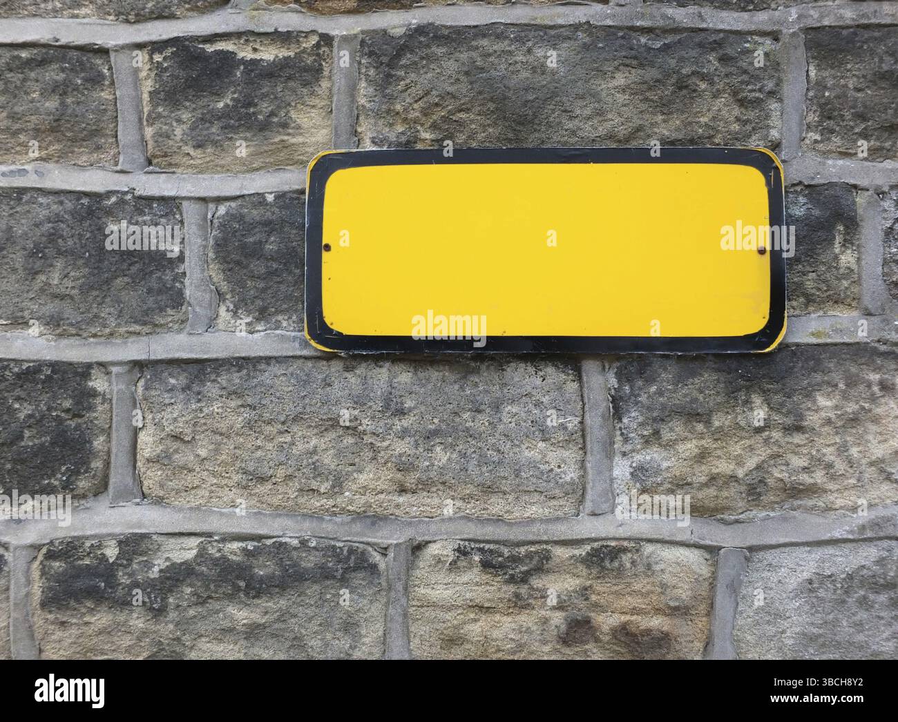 Un cartello metallico giallo vuoto con spazio vuoto per copiare il testo su un vecchio sfondo in pietra Foto Stock