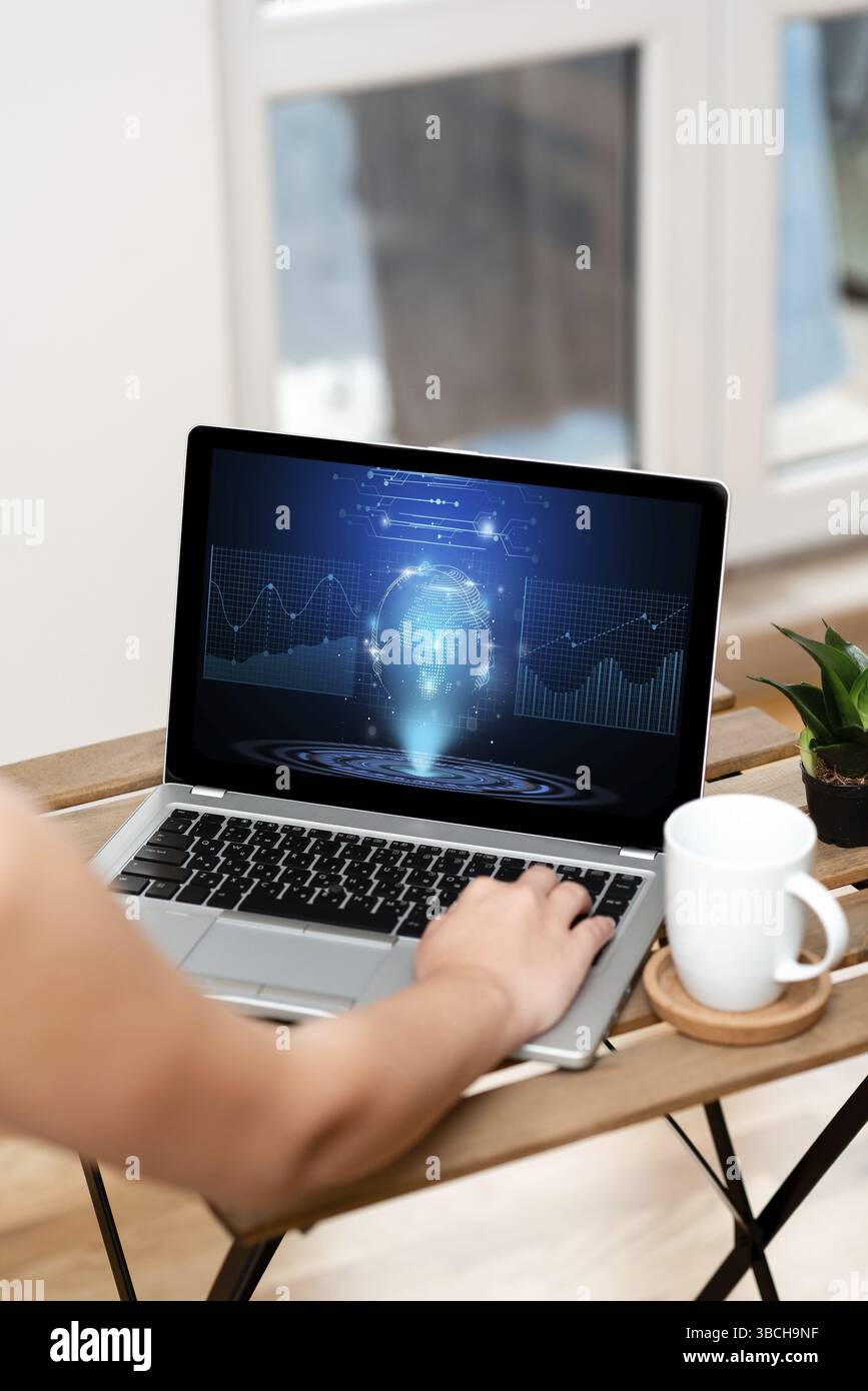 Mentre scrivi sul laptop accanto a Coffe Mug e Plant Working from Home Foto Stock