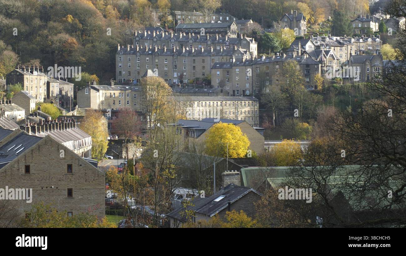 Una vista panoramica del ponte della città di hebden nell'ovest dello yorkshire con strade di case in pietra su ripide colline alla luce del sole autunnale circondate da alberi Foto Stock