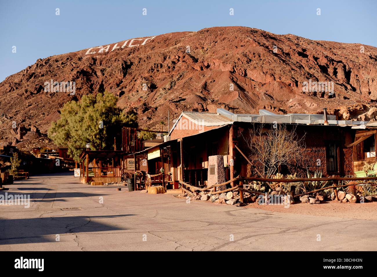 Città deserta con edifici aspri e una collina che mostra grandi lettere bianche sotto il cielo limpido. Road Trip USA Foto Stock