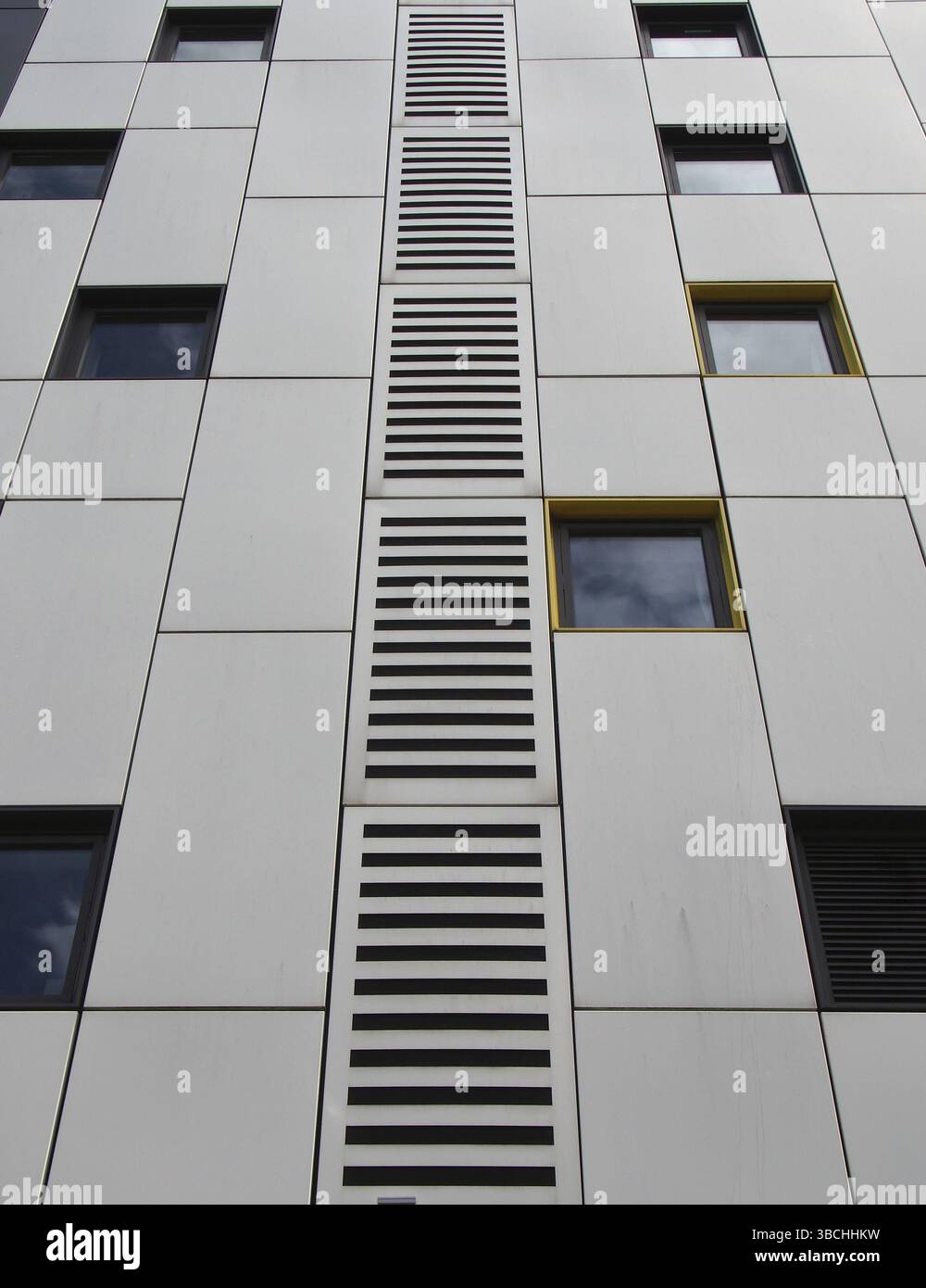 Primo piano di pannelli di rivestimento in metallo color argento in un edificio moderno con finestre ripetute e design geometrico a griglia Foto Stock