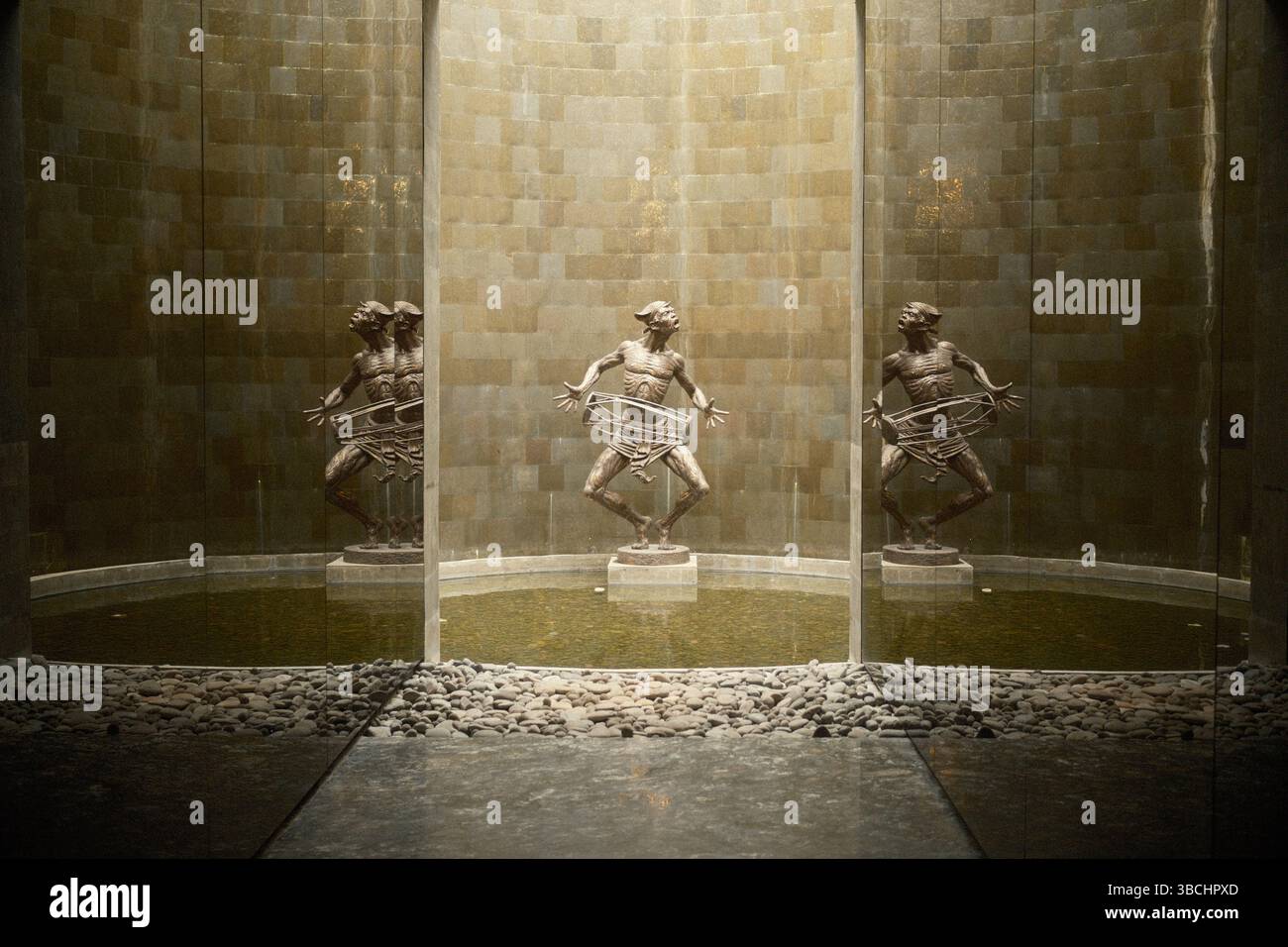 Una scultura artistica in bronzo con riflessi a specchio e illuminazione naturale che amplifica l'armonia visiva Foto Stock