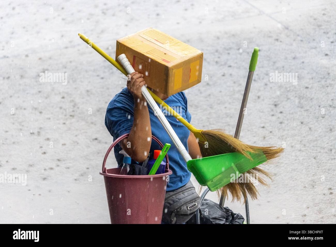 Protezione creativa per gli addetti alle pulizie in caso di pioggia battente Foto Stock