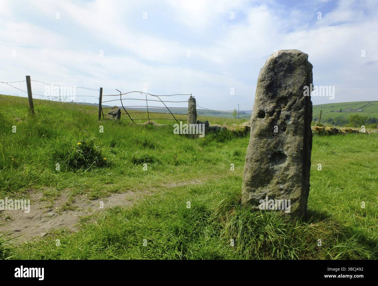 Alto cancello in pietra o vecchio cancello con vecchia recinzione e cancello metallico nei pascoli dei pennini con prati estivi e campi in collina in lontananza Foto Stock