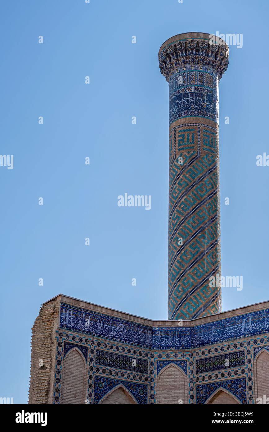 Un alto minareto con bande decorative blu si erge presso il Mausoleo di Gur e Amir a Samarcanda, Uzbekistan, che rappresenta lo stile religioso timuride. Foto Stock