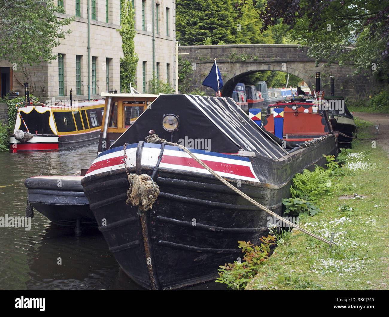 Vecchie chiatte e case galleggianti ormeggiate sul canale rochdale nel ponte di hebden, nello yorkshire occidentale Foto Stock