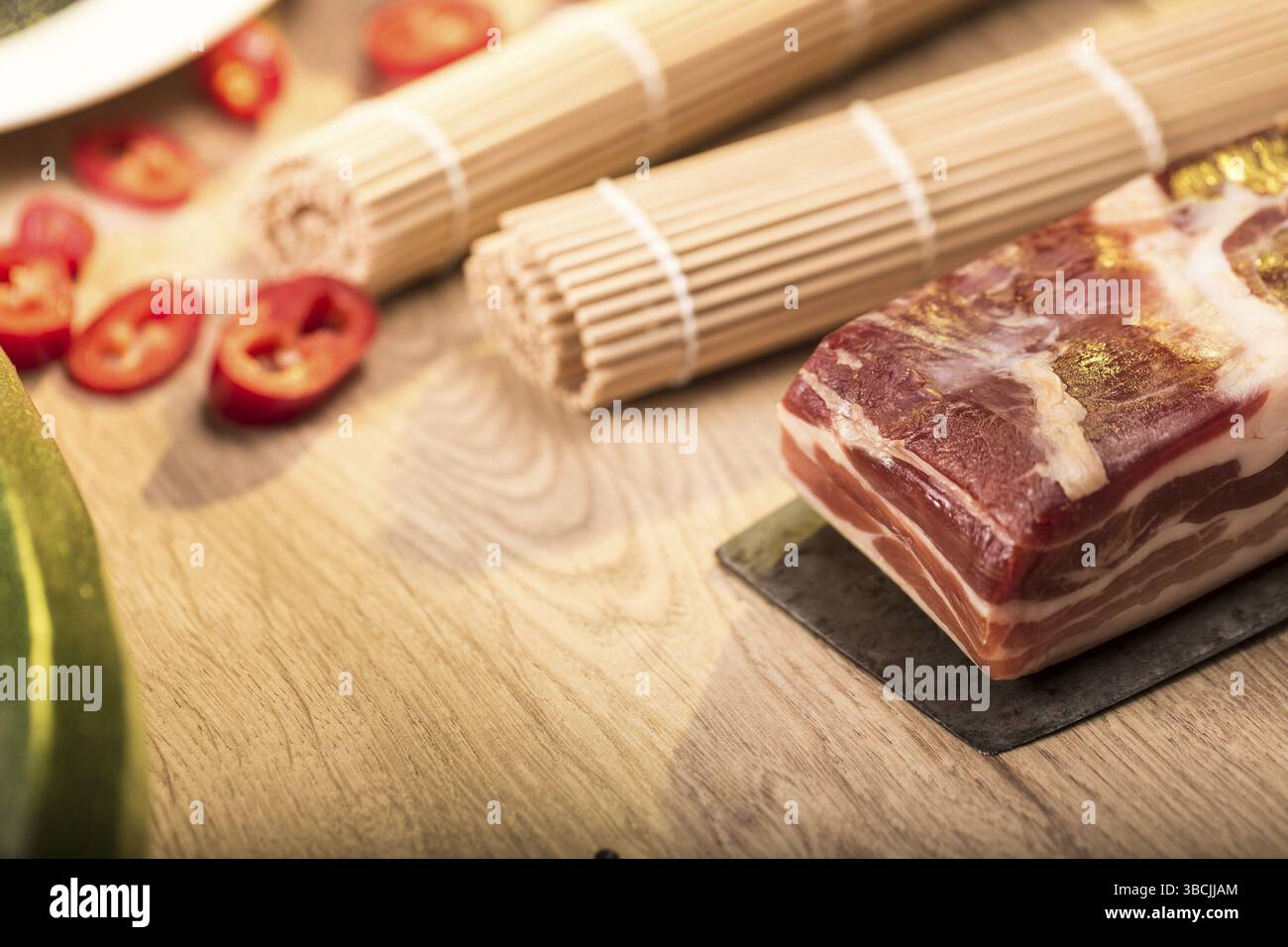 Natura morta con pancetta e coltelli su un piano di lavoro della cucina Foto Stock