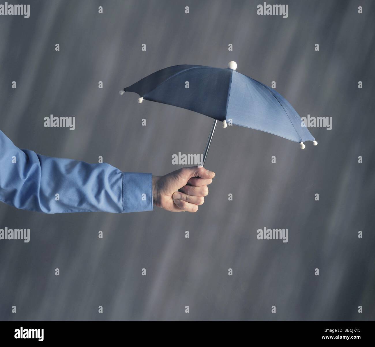 Mano di un uomo d'affari con un ombrello in pioggia, protezione o concetto di sicurezza Foto Stock