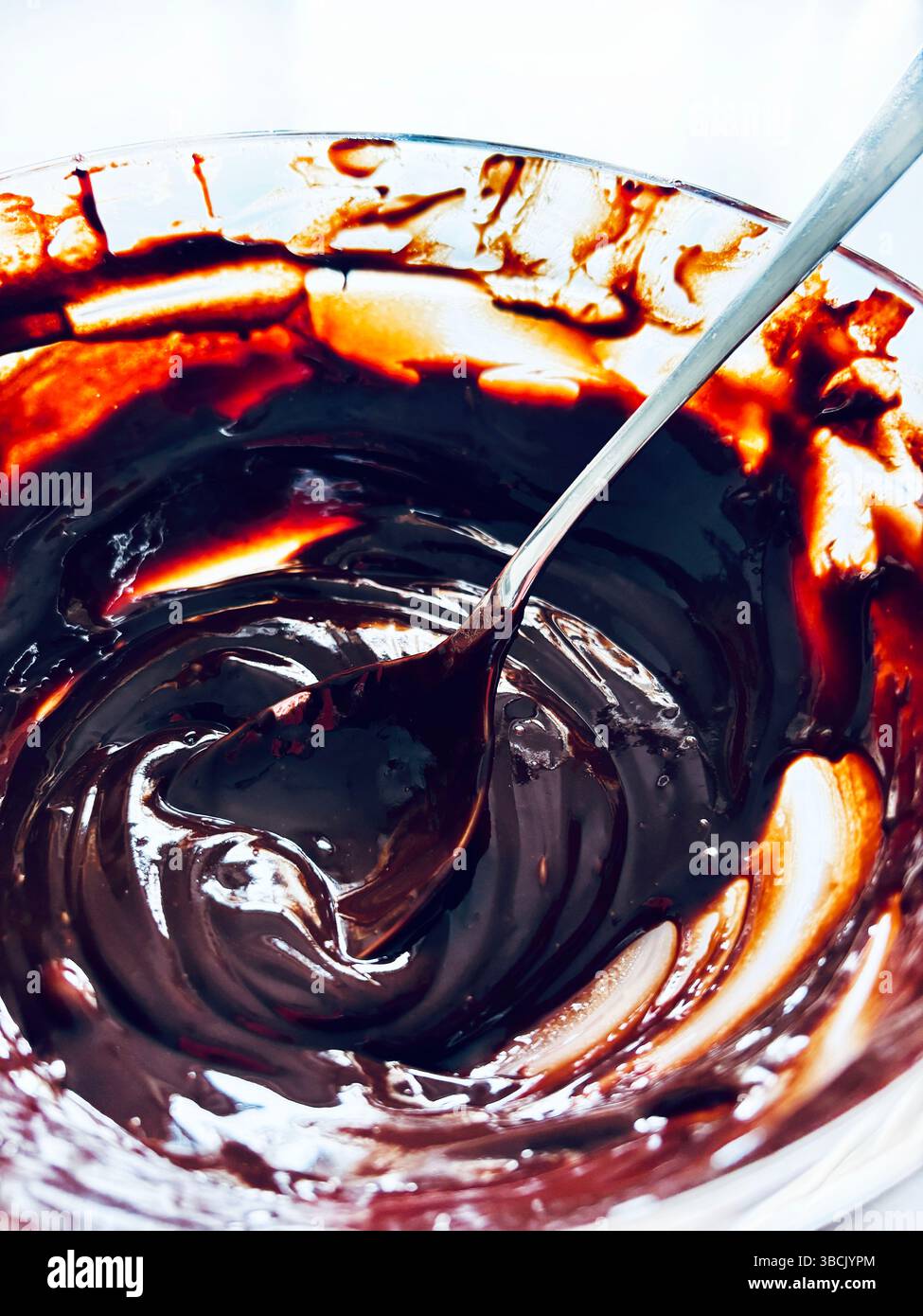 Deliziosa crema di cioccolato in vaso di vetro su un tavolo bianco. Concetto di preparazione dei dolci. Direttamente sopra. Foto Stock