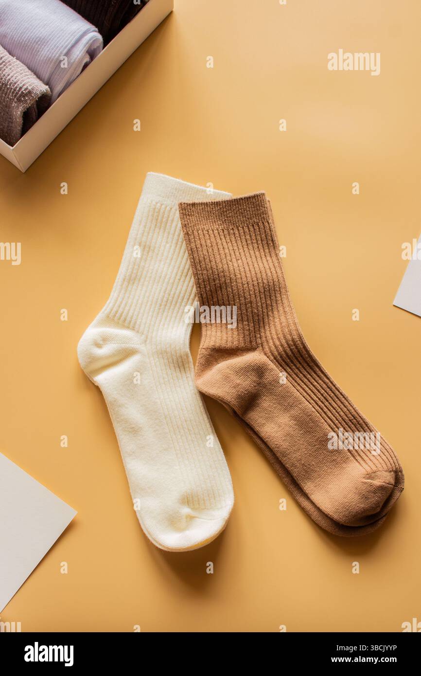 Un paio di comode calze color crema e marrone su sfondo giallo caldo. Ideale per annunci di calzini, idee di confezionamento dei prodotti o un'estetica per la casa allegra. Foto Stock
