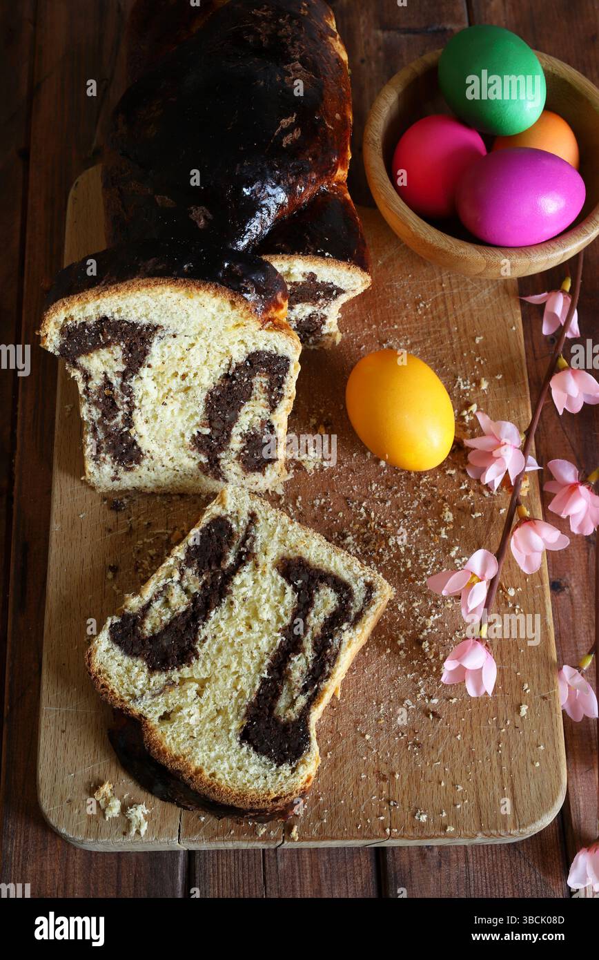 Cozonac. Taglio del tradizionale pane dolce rumeno di Pasqua su un tagliere di legno e uova di Pasqua sullo sfondo. Vacanze gastronomiche dell'Europa orientale. Foto Stock