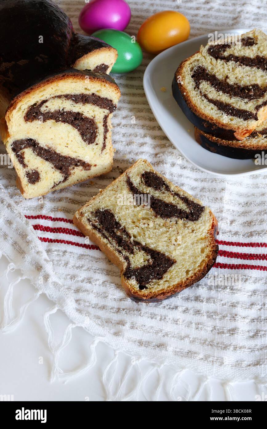 Cozonac. Taglio del tradizionale pane dolce rumeno di Pasqua e delle uova di Pasqua sullo sfondo. Vacanze gastronomiche dell'Europa orientale. Direttamente sopra. Foto Stock