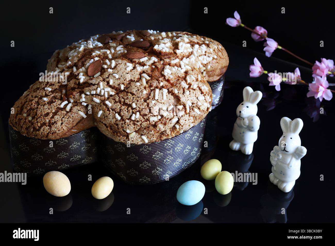 Сolomba Pasquale. Tradizionale pane pasquale dolce italiano condito con zucchero perlato e mandorle candite su sfondo nero. Torta di colomba di Pasqua. Foto Stock