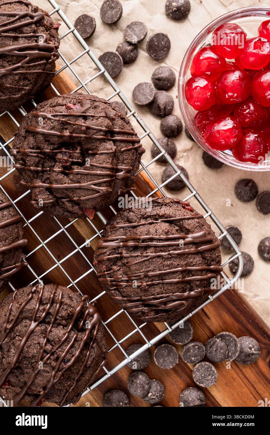 Biscotti alla ciliegia tripla al cioccolato con patatine al cioccolato e ciliegie candite: Biscotti al cioccolato con gocce di cioccolato fondente sulla griglia di raffreddamento a filo Foto Stock