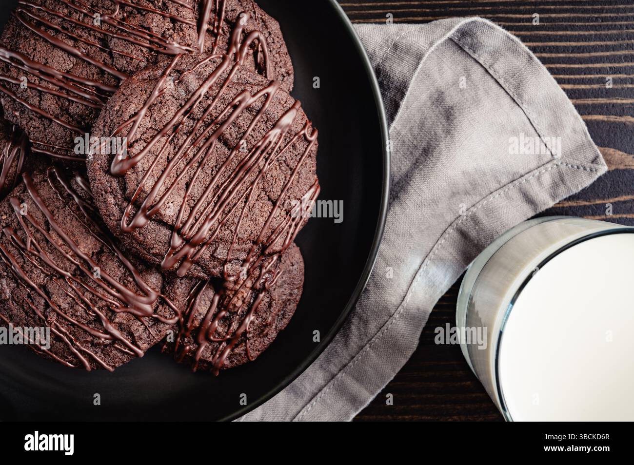 Primo piano del piatto di biscotti alla ciliegia al cioccolato con bicchiere di latte: Dessert con biscotti alla ciliegia al cioccolato impilato su un piatto con una tazza di latte Foto Stock